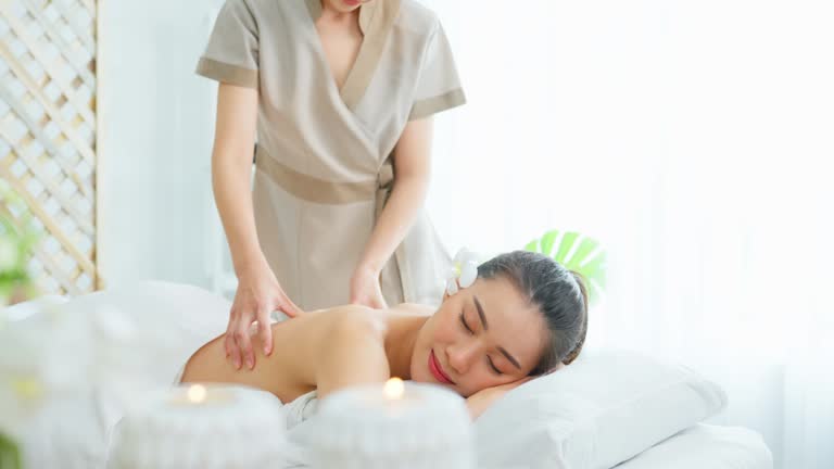 Professional massage session with a relaxed woman receiving back treatment from a Massage therapist Tysons Corner in a calm spa setting.
